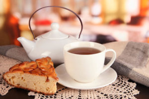 Cup of tea on a saucer, with a dessert tea kettle on the table in historic hotel in Concord, MA