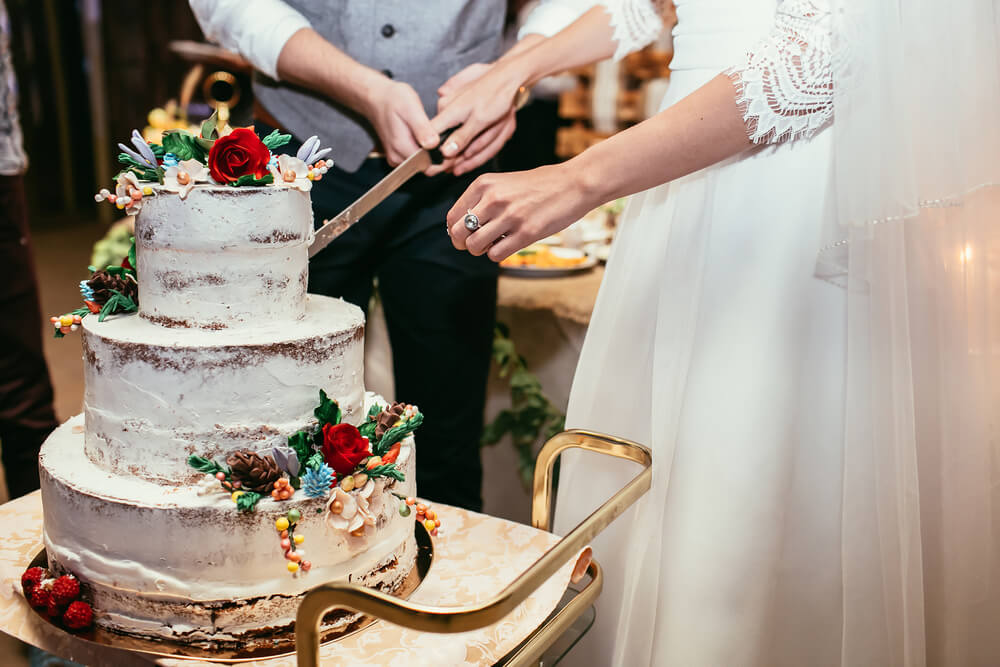 Groom and Bride cut a cake during their Concord Colonial Inn wedding. Only their hands and the cake can be seen.
