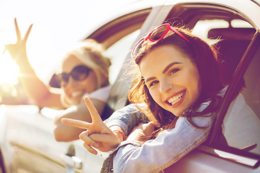 Two women hold up peace signs from their car, on the way to their girl's trip to Concord, near Boston, MA.